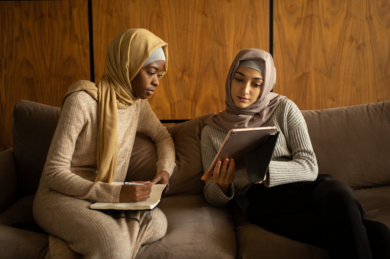 Multiethnic Muslim women using tablet and taking note
